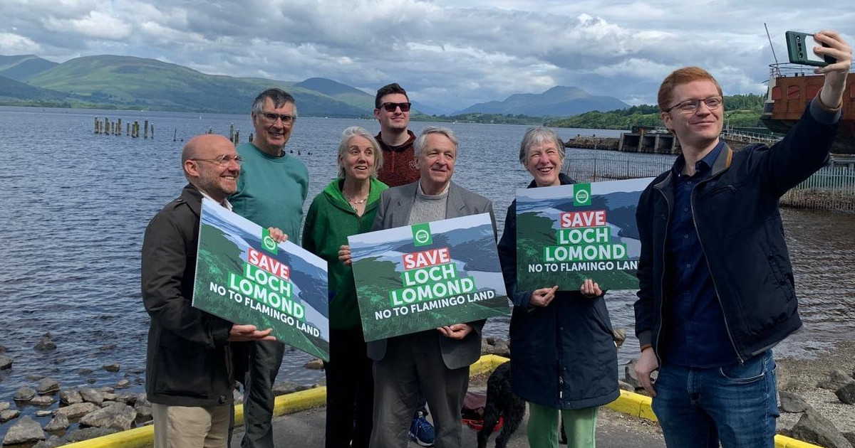 Ross Greer MSP and Patrick Harvie MSP on the banks of Loch Lomond with campaigners, holding 'Save Loch Lomond' boards